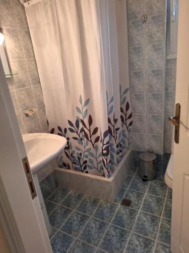 a bathroom with a shower curtain and a sink at Χαρά in Velimákhion