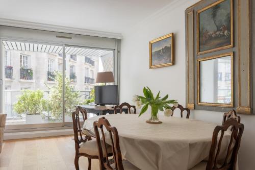 une salle à manger avec une table et des chaises et une fenêtre dans l'établissement Veeve - Refined Retro, à Neuilly-sur-Seine