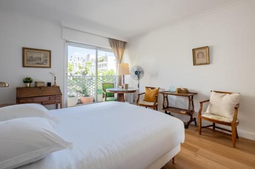 une chambre blanche avec un lit et une fenêtre dans l'établissement Veeve - Refined Retro, à Neuilly-sur-Seine