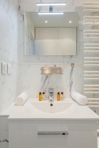 une salle de bain blanche avec un lavabo et un miroir dans l'établissement Veeve - Refined Retro, à Neuilly-sur-Seine