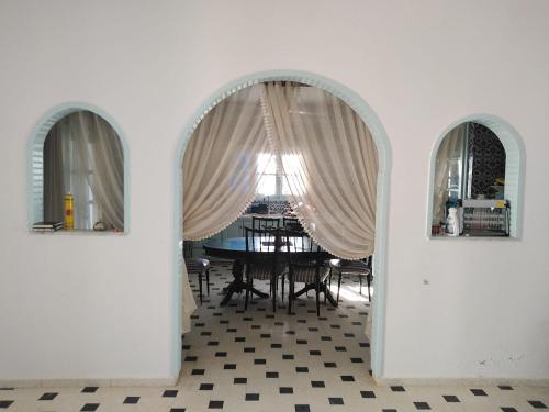 a dining room with a table and two arched windows at VILLA Tej el moulk in Es Somaa