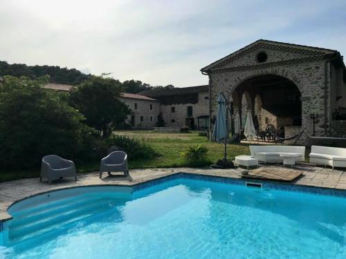 une piscine avec deux chaises et un bâtiment dans l'établissement Métairie du Château, à Aussillon