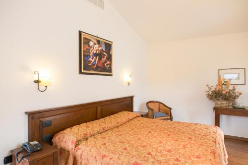 a bedroom with a bed and a picture on the wall at Colleverde Country House & SPA Urbino in Urbino