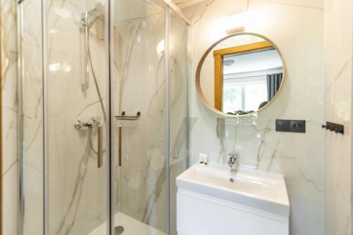 a bathroom with a shower and a sink and a mirror at Apartamenty Na Klifie Przystań 18 Chłapowo in Władysławowo