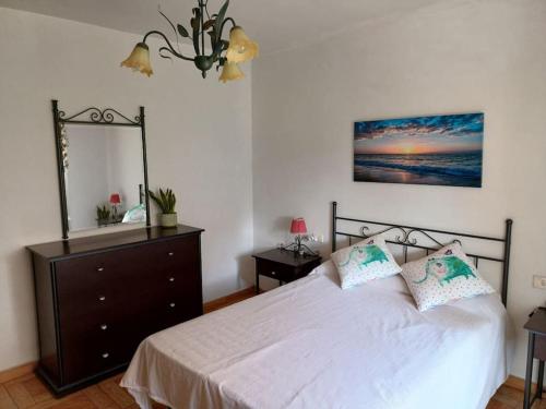a bedroom with a bed with a dresser and a mirror at Casa descanso en familia junto a la playa y rio in Rianjo