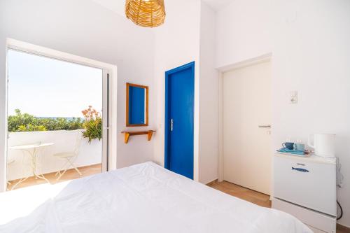 a bedroom with a white bed and a blue door at Babis & Popi Rooms and Studios in Frangokastello