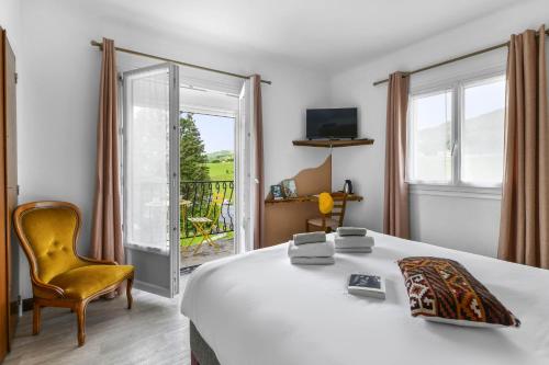 a bedroom with a bed and a chair and a window at Logis Hôtel Restaurant Espelletenia in Larceveau-Arros-Cibits