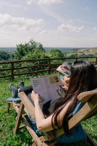 a woman sitting on a bench reading a newspaper at Splendido rustico nella Langa in Clavesana