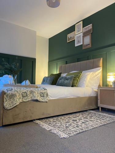 a bedroom with a large bed with a green wall at Ilayda Stays - 22 Alexandra Street in Port Talbot