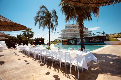 a row of tables with white chairs in front of a pool at Kodra e Godenve in Vilë-Ballaj