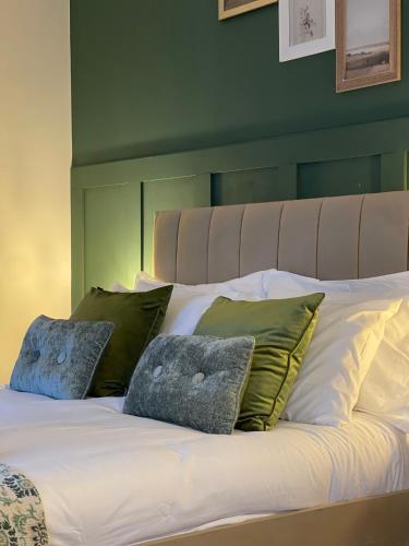 a bed with green and white sheets and pillows at Ilayda Stays - 22 Alexandra Street in Port Talbot