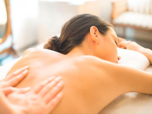 a woman laying on a bed with her backuffed up at Hakuba Tokyu Hotel in Hakuba