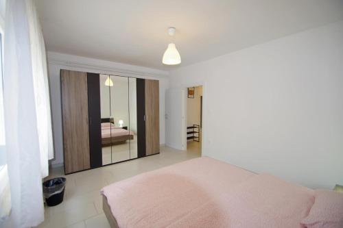a bedroom with a pink bed and a mirror at Apartments Nikolina in Rakalj
