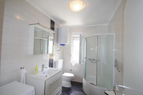 a white bathroom with a shower and a toilet at Apartments Nikolina in Rakalj