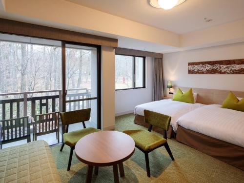 a hotel room with two beds and a balcony at Hakuba Tokyu Hotel in Hakuba