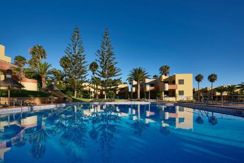 a large swimming pool with palm trees and buildings at Atlantic Garden Beach Mate in Corralejo
