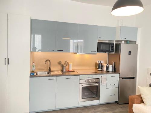 une cuisine avec des armoires blanches et un réfrigérateur en acier inoxydable dans l'établissement Chic Appartement 2 bedrooms PHANTHEON NOTRE DAME, à Paris