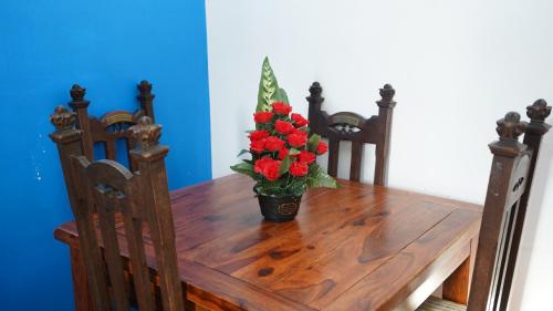 a wooden table with a vase of red flowers on it at 59B Comfortable 3 Bedroom House By Easy 2 Manage in Cranford