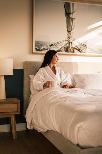 a woman sitting in bed in a hotel room at Hôtel Expérience - Quartier Des Marinas in Magog-Orford