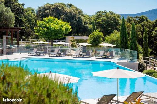 une grande piscine avec chaises et parasols dans l'établissement Appartement dernier étage avec spa privatif sur grande terrasse, à Porto-Vecchio