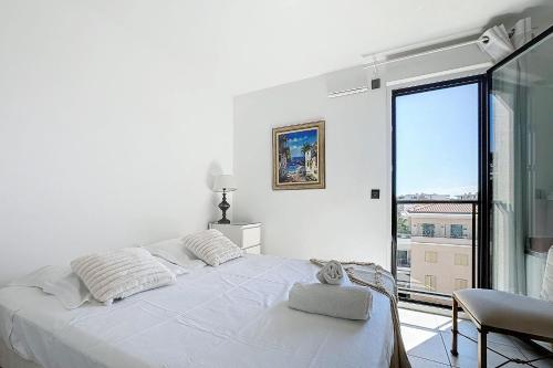 une chambre blanche avec un lit et une grande fenêtre dans l'établissement Le Secret Garden - 3-room apartment with pool - Palm beach, à Cannes