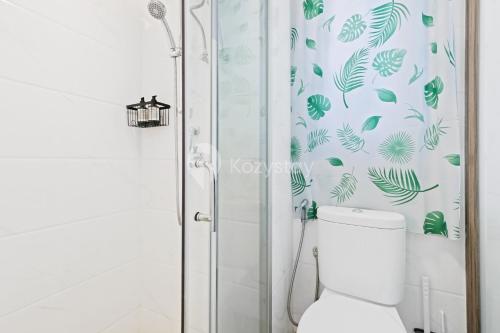 a bathroom with a toilet and a shower with green leaves at Caleido by Kozystay - BSD in Tangerang