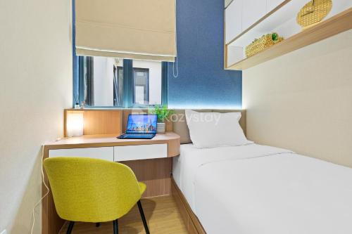 a small room with a bed and a desk with a laptop at Caleido by Kozystay - BSD in Tangerang
