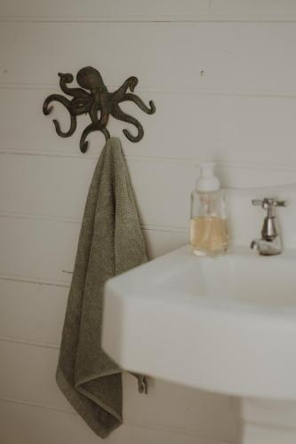 a towel hanging on a wall next to a sink at Quaint and intimate 1-bed seaside cottage in Bridport
