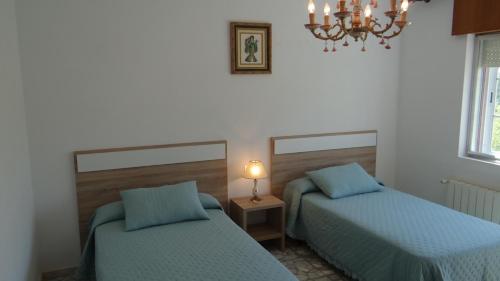 a bedroom with two beds and a lamp on a table at Casa de Lolo en Lariño cerca de la playa in San Mamede de Carnota