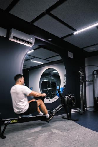 a man sitting on a treadmill in a gym at Hôtel Expérience - Quartier Des Marinas in Magog-Orford