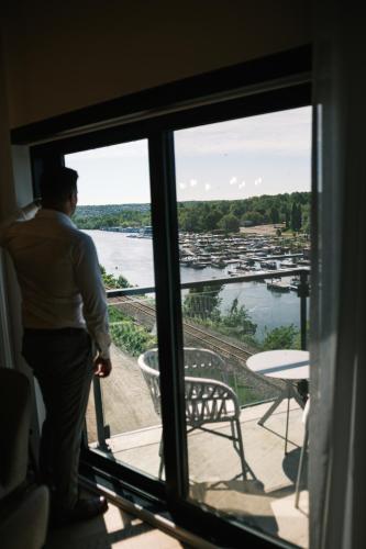 a man standing on a balcony looking out the window at Hôtel Expérience - Quartier Des Marinas in Magog-Orford