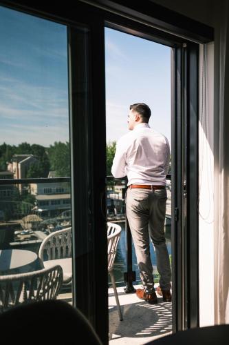 a man standing on a balcony looking out the window at Hôtel Expérience - Quartier Des Marinas in Magog-Orford