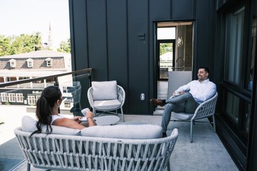a man and a woman sitting on chairs on a porch at Hôtel Expérience - Quartier Des Marinas in Magog-Orford