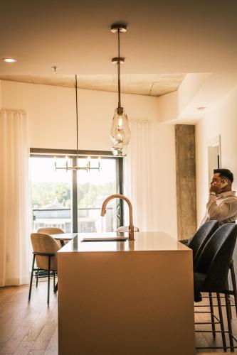 a man sitting in a chair in a living room at Hôtel Expérience - Quartier Des Marinas in Magog-Orford