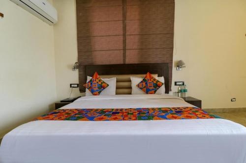 a bedroom with a large white bed with colorful pillows at FabHotel Narula in Dehradun