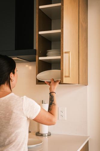 a woman holding a plate in a kitchen cabinets at Hôtel Expérience - Quartier Des Marinas in Magog-Orford