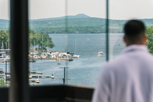 a man looking out of a window at a marina at Hôtel Expérience - Quartier Des Marinas in Magog-Orford