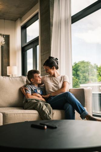 a woman sitting on a couch with a boy at Hôtel Expérience - Quartier Des Marinas in Magog-Orford