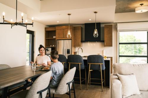 a woman and child sitting at a table in a kitchen at Hôtel Expérience - Quartier Des Marinas in Magog-Orford