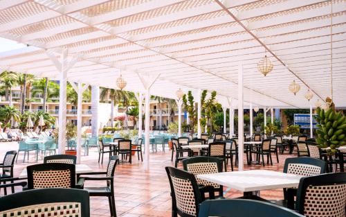 a restaurant with tables and chairs and a pool at Club Hotel Drago Park in Costa Calma