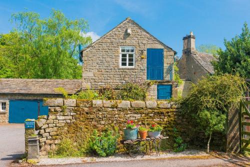 a stone house with blue doors and a stone wall at Heathy Lea Barn Chatsworth Estate in Baslow