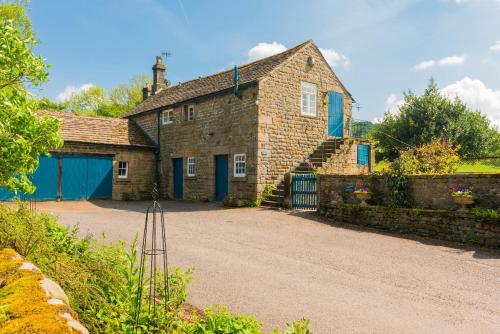 an old brick house with blue doors and a driveway at Heathy Lea Barn Chatsworth Estate in Baslow
