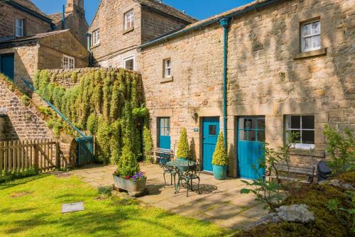 a courtyard of a brick building with a table and chairs at Stable Cottage Chatsworth Estate in Baslow