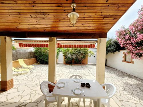 une table et des chaises sur une terrasse avec un plafond en bois dans l'établissement Charmante villa T3 avec terrasse à 500m de la plage, parfait pour 4 personnes - FR-1-794-131, à Canet