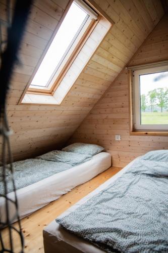 two beds in a attic room with a window at Alicjówka - domek in Marciszów