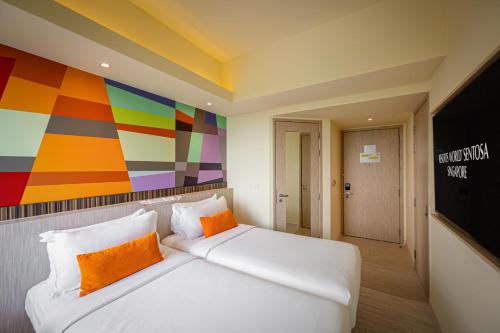 a bedroom with a large white bed with orange pillows at Genting Hotel Jurong in Singapore