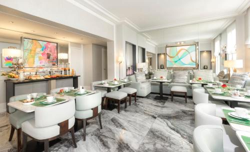 a restaurant with white tables and white chairs at Hôtel Du Bois Champs-Elysées in Paris