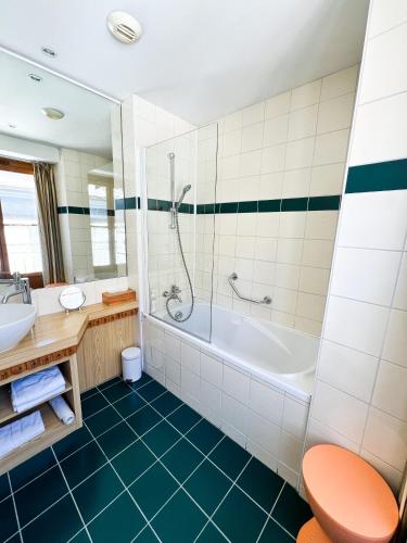 a bathroom with a tub and a toilet and a sink at Hôtel Le Bois Joli in Cauterets