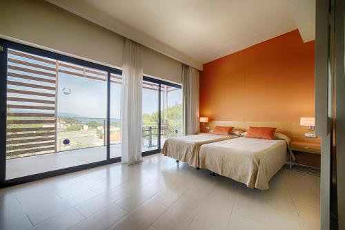 a bedroom with a bed and a large window at Ohtels Les Oliveres in Perelló