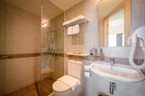 a bathroom with a toilet and a sink and a shower at Genting Hotel Jurong in Singapore